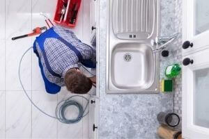 Plumber Working Under Sink